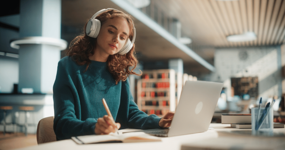 Woman Writing at Computer With Headphones