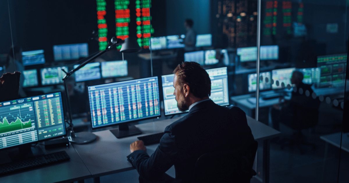 Male Broker Trading on Multiple Screens