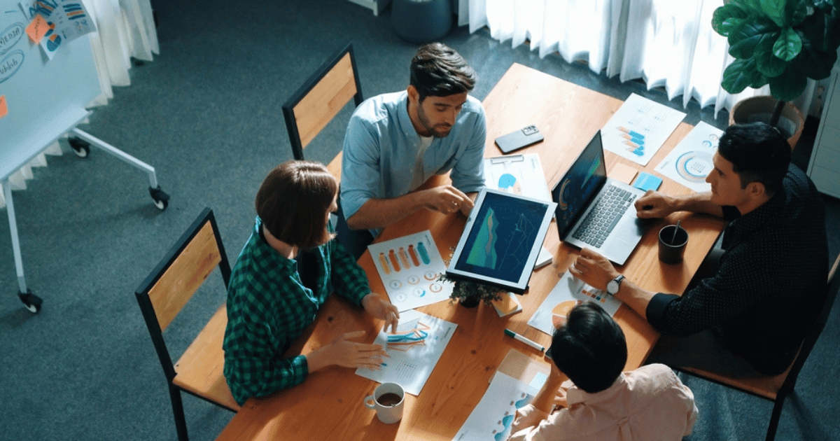 People at Company Sitting in Board Room With Charts and Laptop